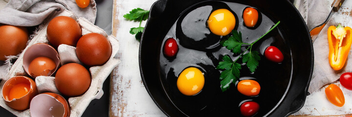 Wall Mural - Raw eggs in pan with herbs and seasoning on gray background, prepared food for breakfast.