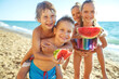 Children play by the sea and eat watermelon. High quality photo.