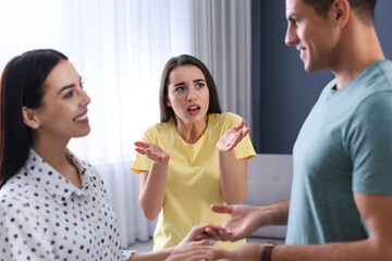 Wall Mural - Unhappy woman feeling jealous while couple spending time together at home