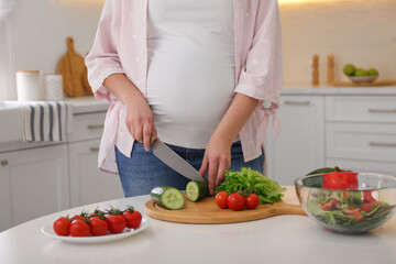 Canvas Print - Young pregnant woman preparing vegetable salad at table in kitchen, closeup. Healthy eating