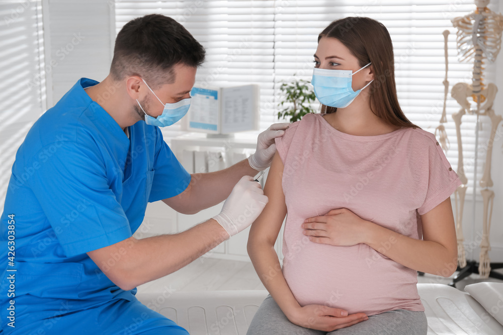 Doctor vaccinating pregnant woman against Covid-19 in clinic - obrazy, fototapety, plakaty 