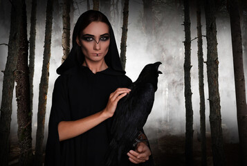 Wall Mural - Mysterious witch with raven  in foggy forest. Fantasy world