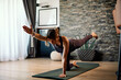 © chika_milan - A middle-aged woman practicing yoga at home while kneeling on a yoga mat.