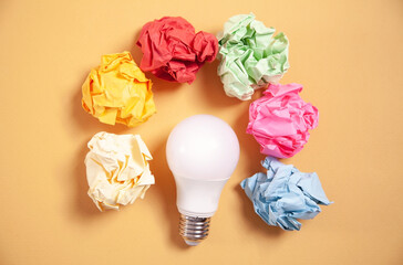 Wall Mural - Colorful paper balls and light bulb on yellow background.