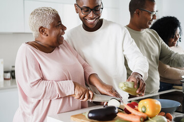 Wall Mural - Happy black family cooking inside kitchen at home - Main focus on mom face