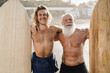 Multi generational surfer friends having fun on the beach after surf session - Focus on faces