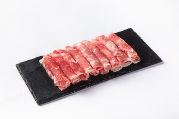 Closeup of fresh raw lamb roll slices on a wooden board isolated on a white background