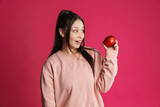 Fototapeta Mapy - Asian excited woman looking aside while posing with apple