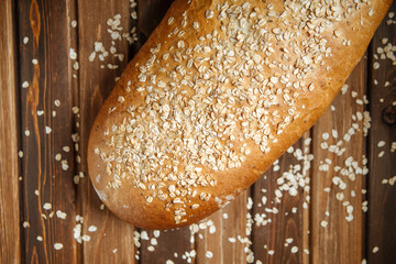 Closeup on fresh baked loaf of bread with oats on the wooden table