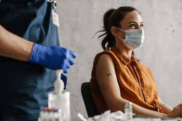 Sick woman in medical mask getting a vaccine shot