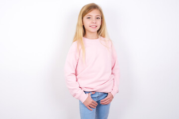 Wall Mural - Portrait of successful beautiful caucasian little girl wearing pink hoodie over white background, smiling broadly with self-assured expression. Confidence and business concept.