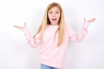 Wall Mural - beautiful caucasian little girl wearing pink hoodie over white background raising hands up, having eyes full of happiness rejoicing his great achievements. Achievement, success concept.