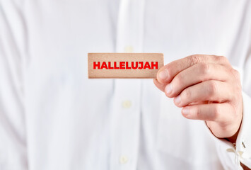 Male hand holds a wooden block with the word hallelujah.