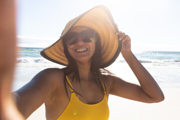 Wall Mural - Smiling mixed race woman on beach holiday taking selfie