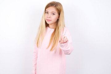 Wall Mural - No sign gesture. Closeup portrait unhappy beautiful caucasian little girl wearing pink hoodie over white background raising fore finger up saying no. Negative emotions facial expressions, feelings.