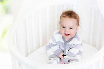 Wall Mural - Baby in a white crib. Child in bed.