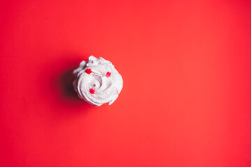 Fresh marshmallows on a red background. Zephyr, meringue. The concept of home-cooked food, sweets. Minimalism, top view, flat lay, copyspace.