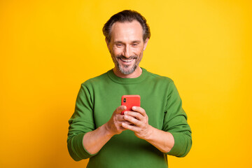 photo of cheerful man hold telephone look screen wear green pullover isolated bright yellow color ba