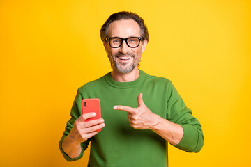 Poster - Photo of handsome man hold phone indicate forefinger wear eyewear green pullover isolated yellow color background