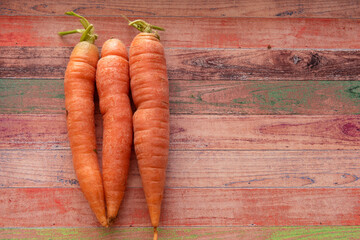 Wall Mural - Top view of three carrots on a colored wooden board