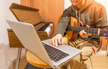 man enjoy playing guitar and learning music lesson online from internet in living room. e-learning c