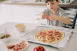 © Olga Krivokoneva - Little kid boy making pizza sitting at the table on the kitchen. Children helping in cooking lifestyle image