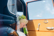 © Alexander Kladov - Wedding bouquet in hands of bride in black retro car with blue sky in background