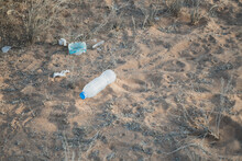 Plastic Water Bottle And Garbage Or Trash Pollution In The Desert Sand. Environmental Conservation And Plastic Concepts.