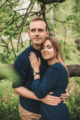 Wall Mural - Handsome young guy with a girl stand in the spring garden. Romantic couple are walking in the park. Happy relationship concept