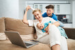 © serhiibobyk - Smiling young woman with her two sons sitting on couch and having video chat on wireless laptop. Happy family using technology at home.