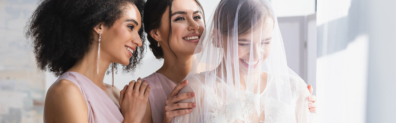 Poster - young bride in veil laughing near happy interracial bridesmaids, banner.