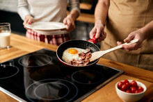Close-up Of Man Preparing Fried Eggs With Bacon For Breakfast At Home.