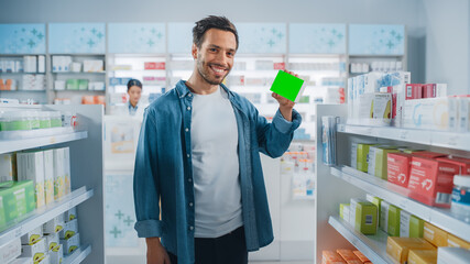 Wall Mural - Pharmacy Drugstore: Portrait of Handsome Latin Man Holding Mock-up Template Medicine Package with Tracking Markers, Looking at Camera, Smiling Happily. Customer Recommending Best Product