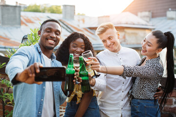 Wall Mural - Cheerful mixed race friends toasting with alcoholic drinks and taking selfie on modern smartphone. Young male and female people having party time with fun.