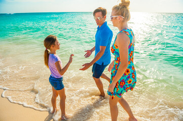 Family at the beach, father and daughter playing, running on the shore, dressed in colorful tropical outfits