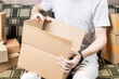 © Andrii - male person indoors unpack cardboard parcel package. men opening box. delivery service concept. online shopping conceptual