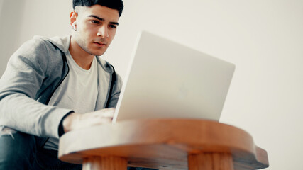 A programmer is sitting in wireless headphones and typing on a computer. A freelance designer works at home on a laptop in a program for layout design. Copy space.