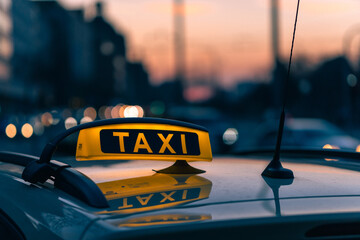 Poster - A close-up shot of a taxi sign in the warm colours of sunset with bokeh lights in the background.