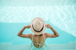 © Jo Panuwat D - Happy woman in white swimsuit swimming in luxury pool hotel, young female with hat enjoy in tropical resort. Relaxing, summer travel, holiday, vacation and weekend concept