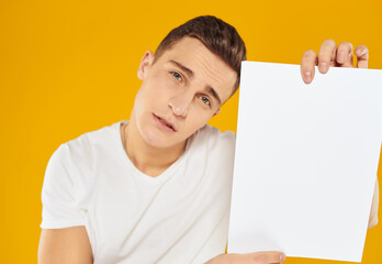 Guy with a white sheet of paper on a yellow background blank business card advertising