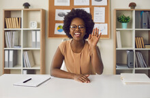 Video Or Online Lesson. African American Woman Waving Hello Smiling Looking At Camera Sitting At Office Desk. Excited Businesswoman Teacher Lecturer Recording Educational Webinar, Greeting Students