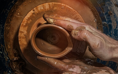 A potter makes a pot on a circle. The hands of the master create from clay. Top view