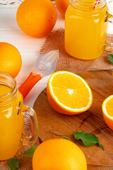 Glass of orange juice and cut oranges on table