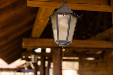 Wall Mural - A vintage black lamp under the ceiling in a wooden farmhouse. Old-fashion lamp. Copy space.