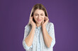 © New Africa - Emotional young woman covering her ears with fingers on purple background