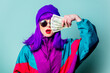 © Masson - Stylish white girl with purple hair and 80s tracksuit hold cash money on blue background