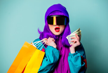 Wall Mural - Stylish girl in cyber punk glasses and 80s tracksuit hold money and shopping bags on blue background