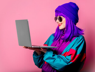 Wall Mural - Stylish girl in 80s tracksuit hold laptop on pink background