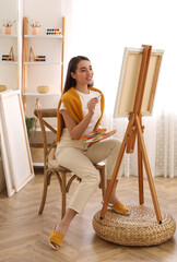 Sticker - Beautiful young woman drawing on easel at home