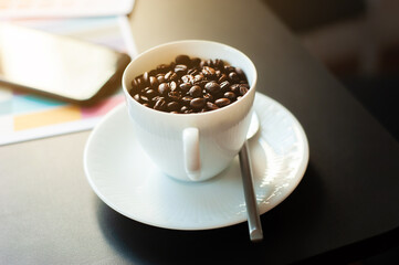 A close up shot of a roasted coffee bean in a coffee cup on the morning desk.